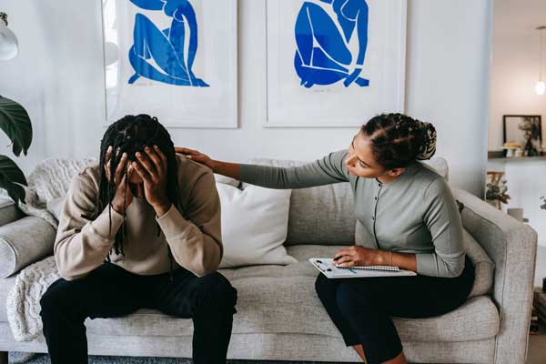 Man facing Sudden Divorce Syndrome with therapist and the therapist puts her hand on his shoulder
