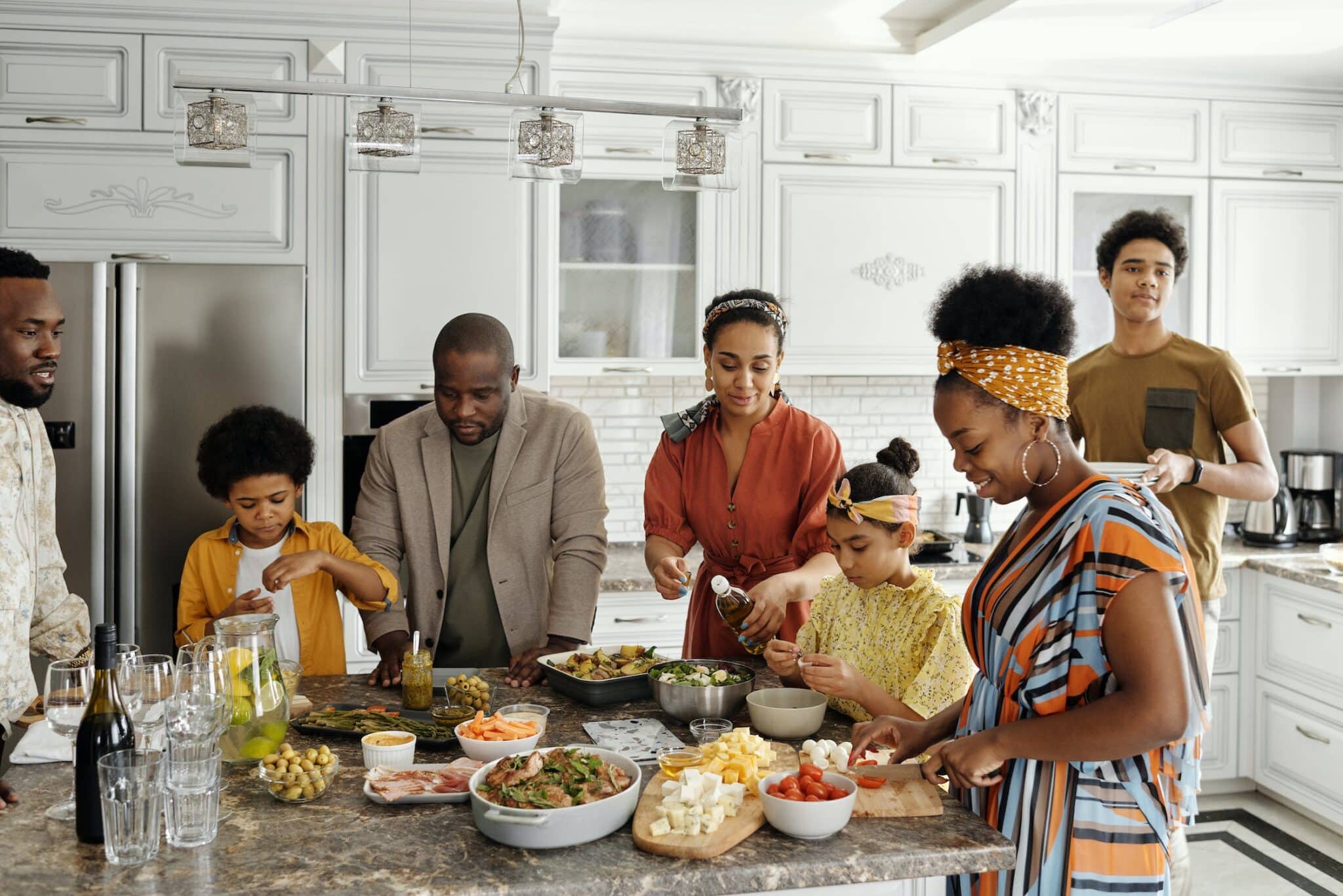 Family getting together around a kitchen island with food